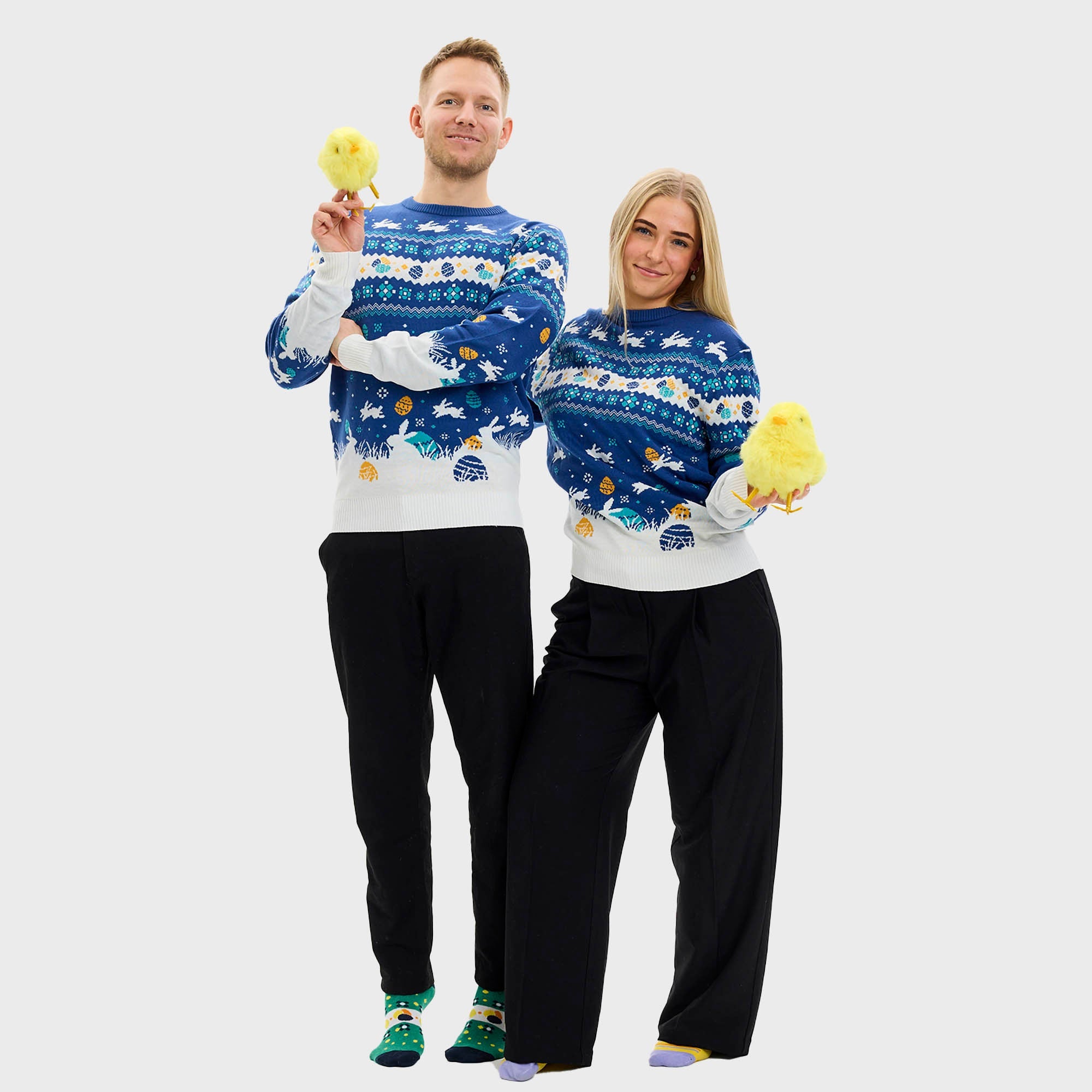 En kvinne poserer iført en blå påskegenser med kaniner på.